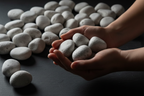 Manos sosteniendo Piedra Bola Blanco Bego, mostrando su escala y acabado redondeado para paisajismo y jardín.