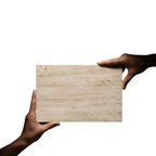 Hands holding a Canteras Naturales Santo Tomás Cantera Beige Rivera stone tile with a natural granular texture.