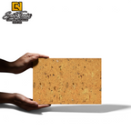 Hands holding a Canteras Naturales Santo Tomás bronze natural stone tile with a warm orange-gold textured surface.