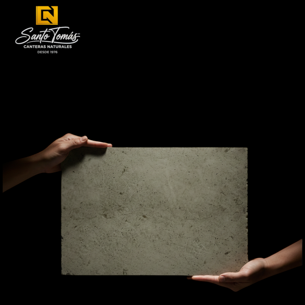 Hands holding a Canteras Naturales Santo Tomás Cantera Gris Puebla stone tile with warm olive-grey organic texture.