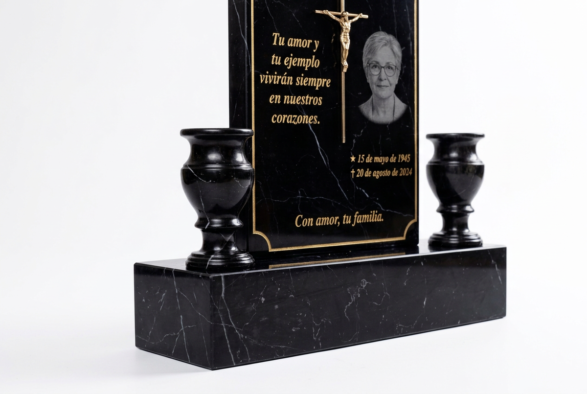 Detalle del Cristo dorado metálico y floreros de mármol negro con fondo blanco.