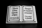 Libro conmemorativo de mármol claro sobre fondo negro con nombre y fechas ficticios.