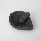 Molcajete tradicional de piedra volcánica basalto con forma de hoja y venas talladas, vista frontal tres cuartos mostrando textura porosa natural