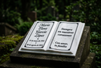 Ambientación ilustrativa de libro conmemorativo de mármol en jardín, con datos ficticios.