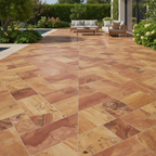 Piso de laja travertino rojo natural con textura porosa en terraza exterior con alberca y muebles de jardín.