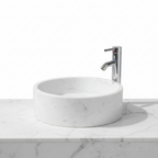 Lavabo ovalín redondo artesanal de mármol Blanco Bego natural de 40 cm con grifo cromado sobre encimera.
